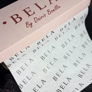 Rollo de papel de seda personalizado con la palabra "BELA" saliendo de una caja de cartón con el texto "BELA By Dairis Bonilla".
