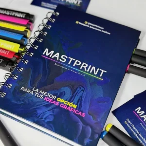 Agenda de espiral con diseño moderno en tonos azules y el logo de Mastprint, junto a marcadores de colores y tarjetas de presentación.